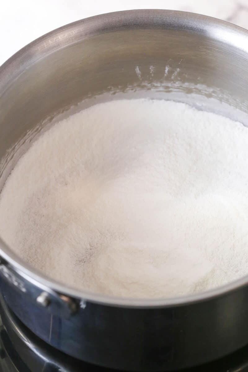 This coconut cream pie is a classic, creamy dessert made from rich coconut custard filling topped with whipped cream in a buttery pie crust. Sugar, cornstarch, and salt added to a saucepan.