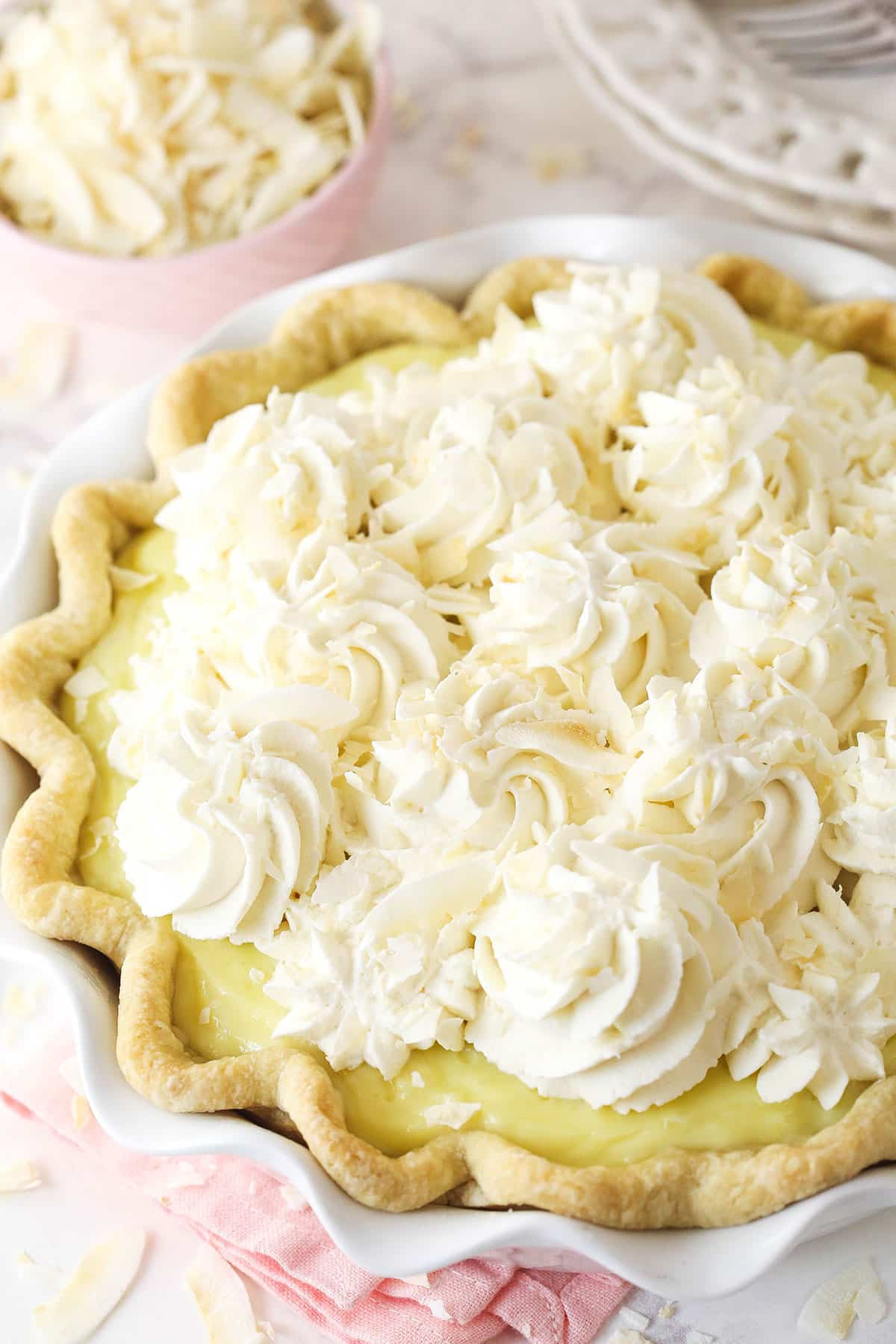This coconut cream pie is a classic, creamy dessert made from rich coconut custard filling topped with whipped cream in a buttery pie crust. Coconut cream pie topped with swirls of whipped cream.