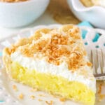 Slice of coconut cream pie with whipped cream and toasted coconut.