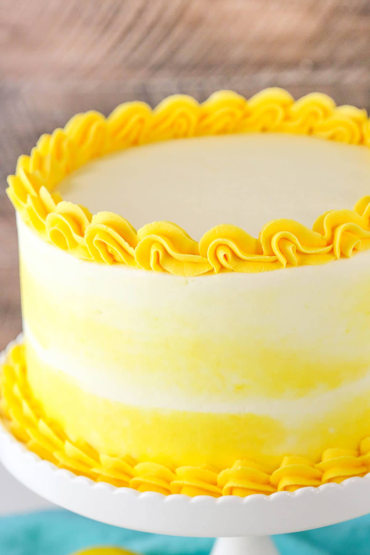 A Frosted and Decorated Citrus Cake with Yellow and White Frosting on a Cake Stand