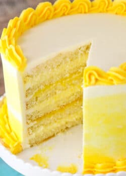 A Lemon Curd Layer Cake on a White Stand with a Slice Removed