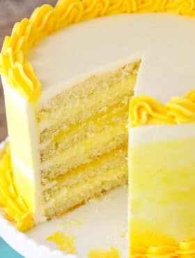 A Lemon Curd Layer Cake on a White Stand with a Slice Removed