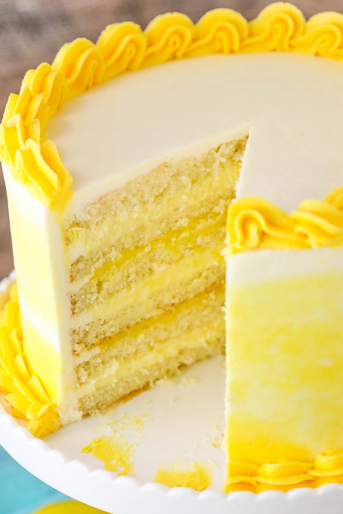 A Lemon Curd Layer Cake on a White Stand with a Slice Removed