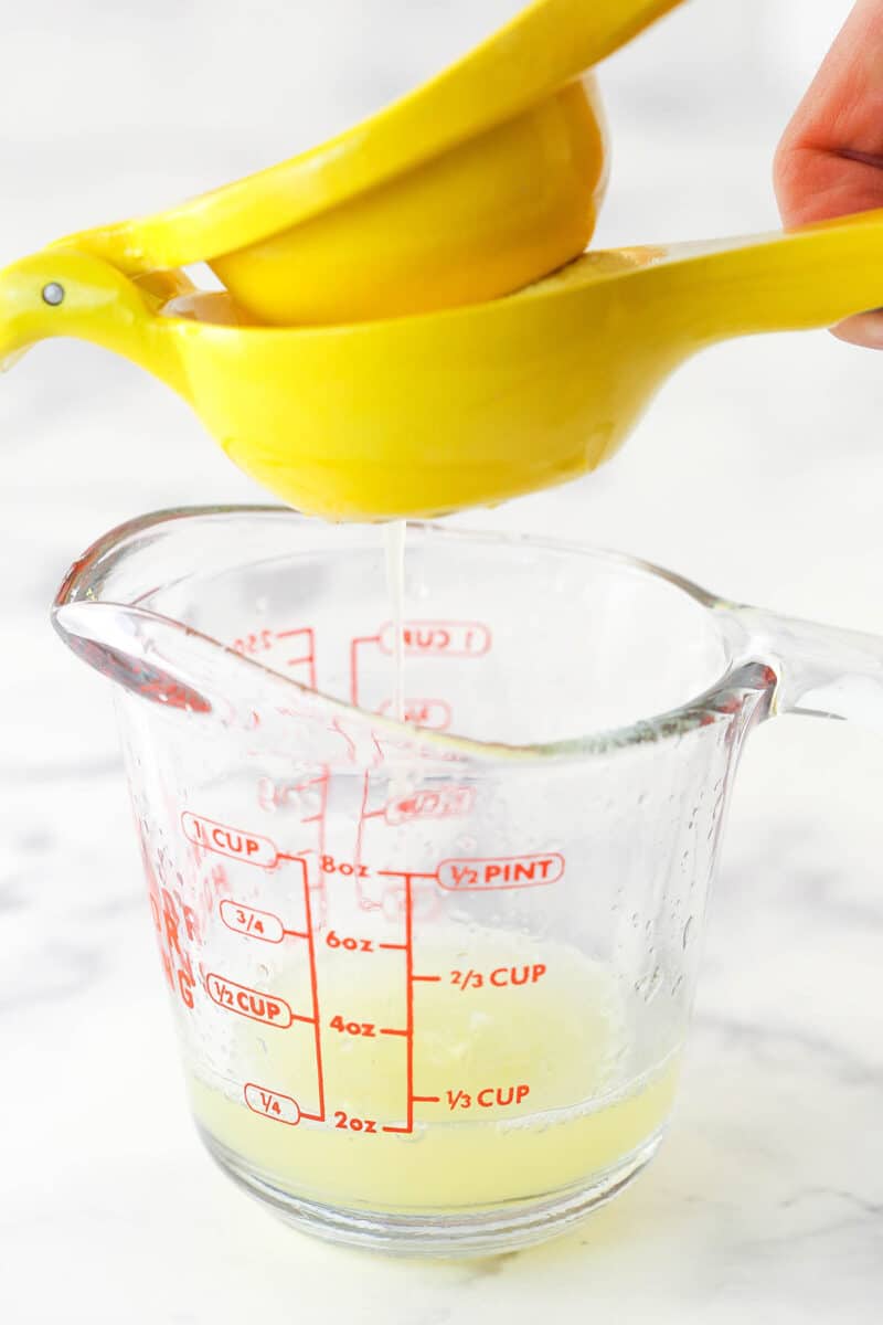 squeezing lemon juice into a measuring cup using a juicer.