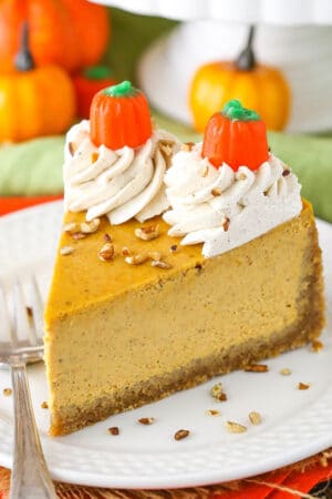 A slice of spiced pumpkin cheesecake on a plate with a fork next to it