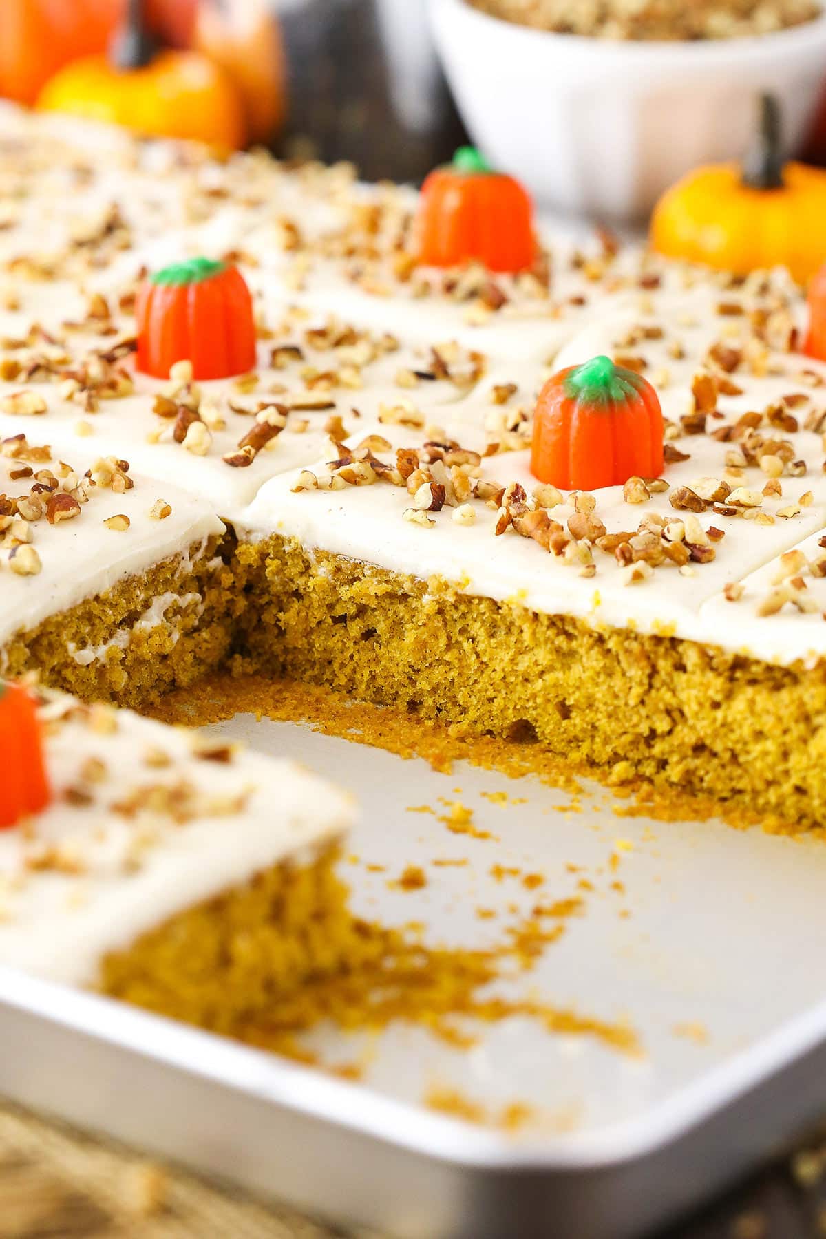 Pumpkin sheet cake in a baking tray, some slices are missing.