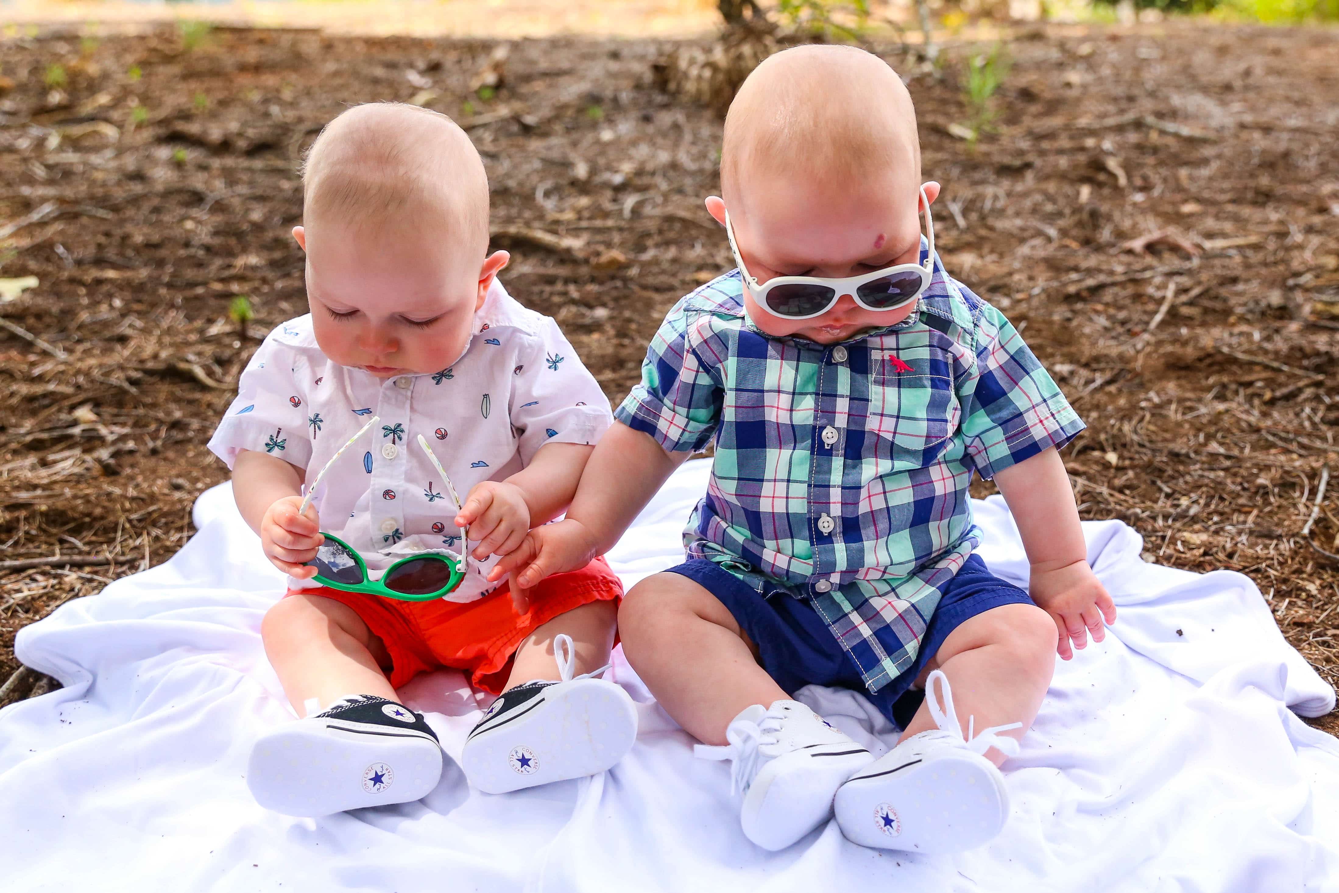 twins sitting on ground with sunglasses