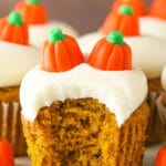 A frosted pumpkin cupcake on a serving platter with a big bite taken out of it