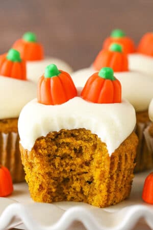 A frosted pumpkin cupcake on a serving platter with a big bite taken out of it