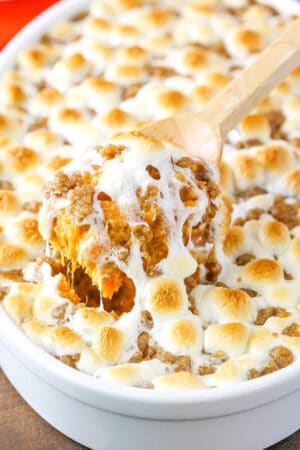 Sweet Potato Casserole with marshmallows in a white dish with a scoop being taken out