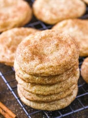 Five snickerdoodles stacked on top of each other with a cinnamon stick beside them