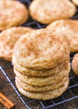 Five snickerdoodles stacked on top of each other with a cinnamon stick beside them