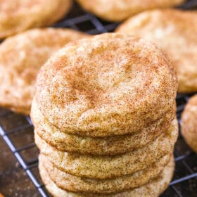 Five snickerdoodles stacked on top of each other with a cinnamon stick beside them