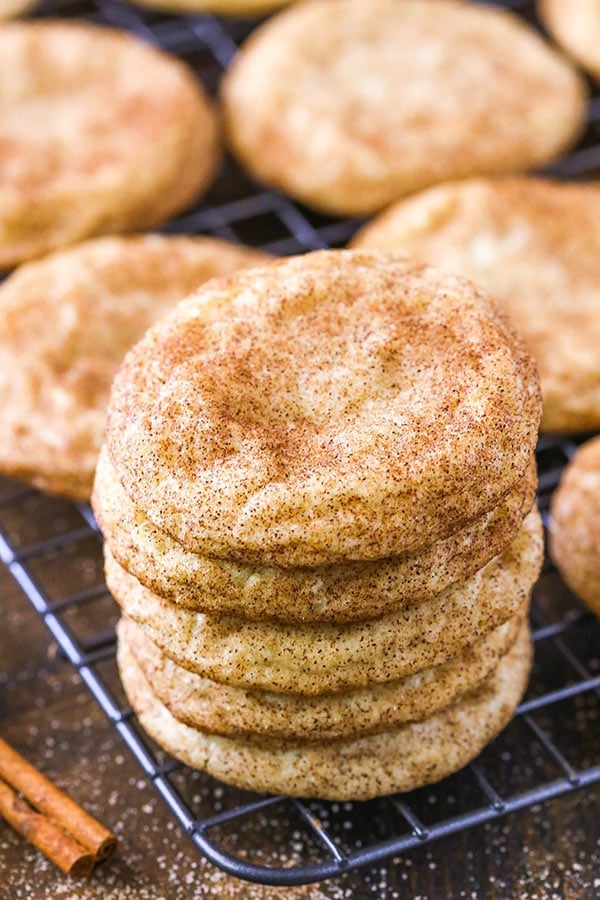 Five snickerdoodles stacked on top of each other with a cinnamon stick beside them