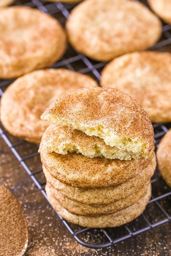 A pile of five snickerdoodle cookies with the top one broken in half to reveal its soft, fluffy interior