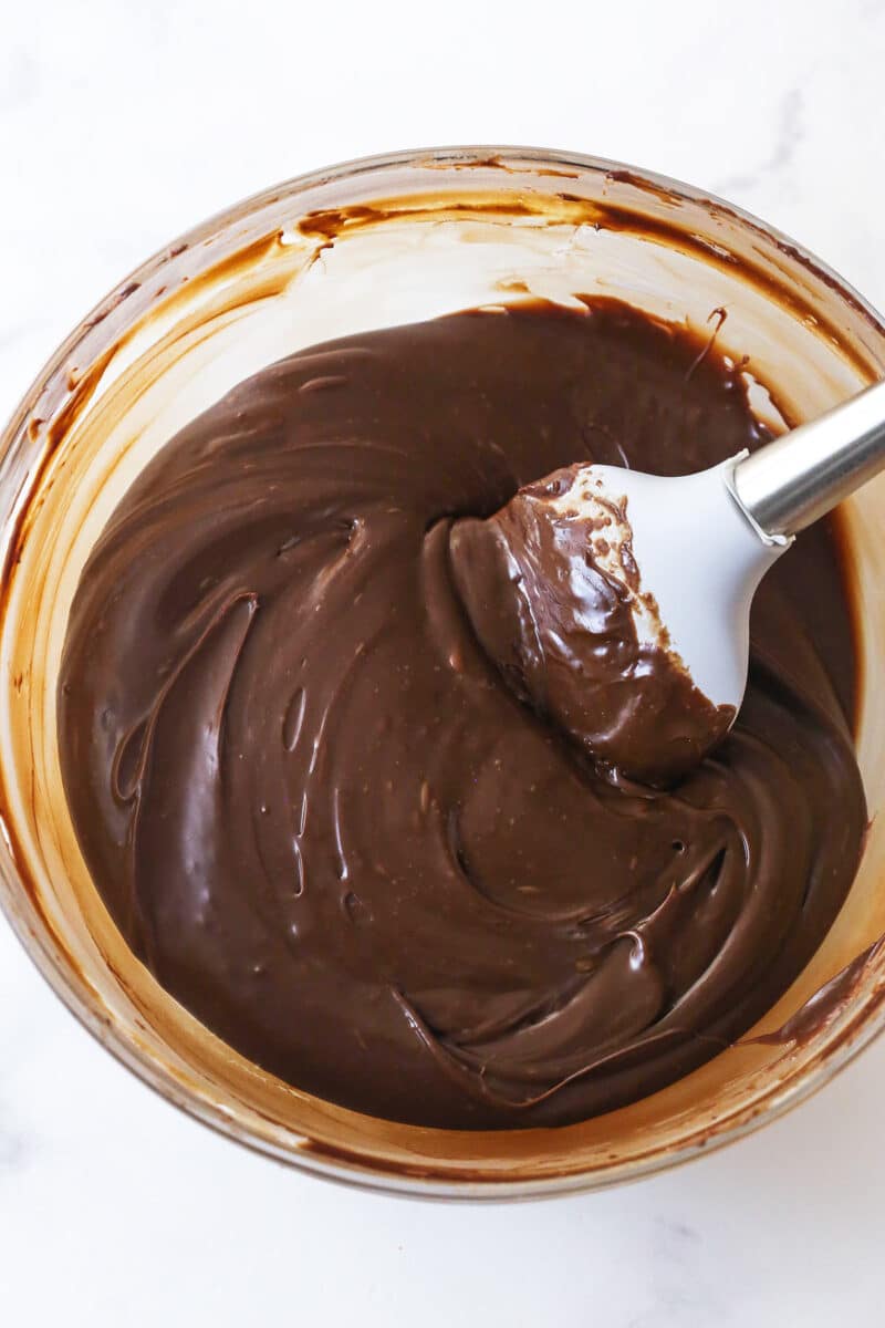 A spatula mixing melted chocolate and sweetened condensed milk