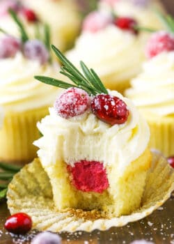 A sparkling cranberry white chocolate cupcake with a bite taken out to reveal the mascarpone filling