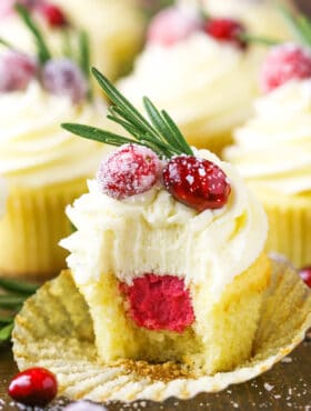 A sparkling cranberry white chocolate cupcake with a bite taken out to reveal the mascarpone filling