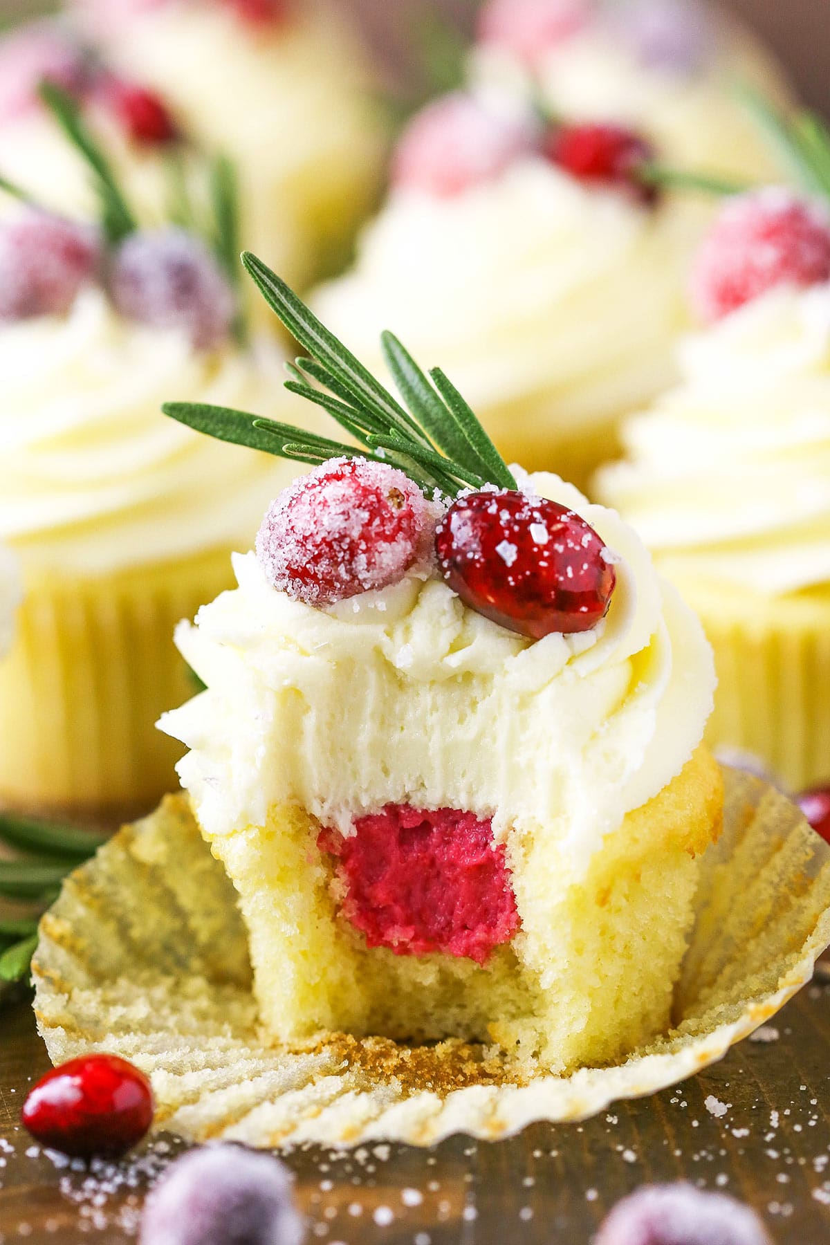 A sparkling cranberry white chocolate cupcake with a bite taken out to reveal the mascarpone filling