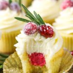 A sparkling cranberry white chocolate cupcake with a bite taken out to reveal the mascarpone filling