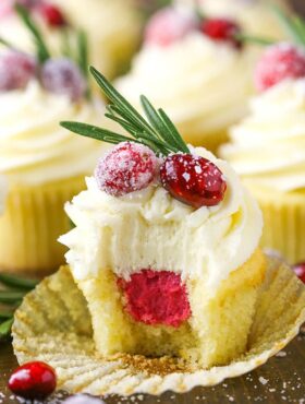 A sparkling cranberry white chocolate cupcake with a bite taken out to reveal the mascarpone filling