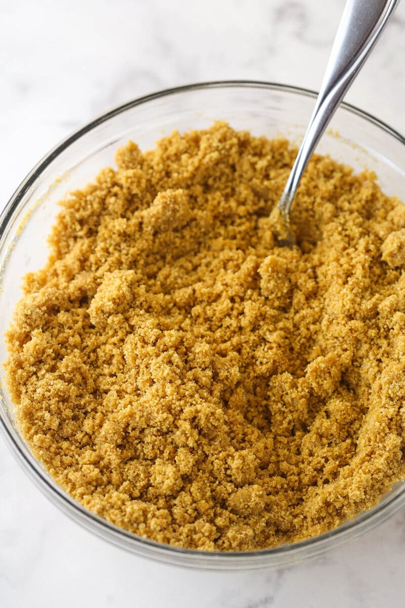 Butter, sugar, and graham cracker crumbs mixed together in a bowl.