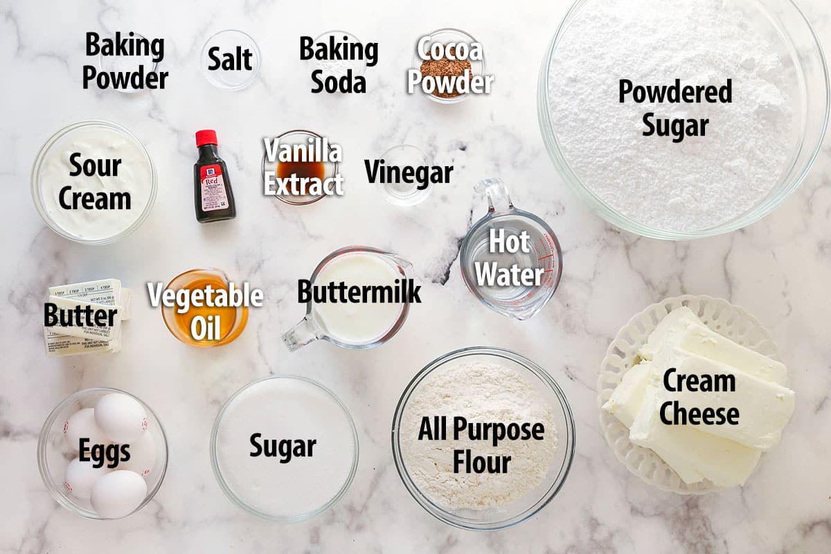 ingredients for red velvet cheesecake cake laid on marble table