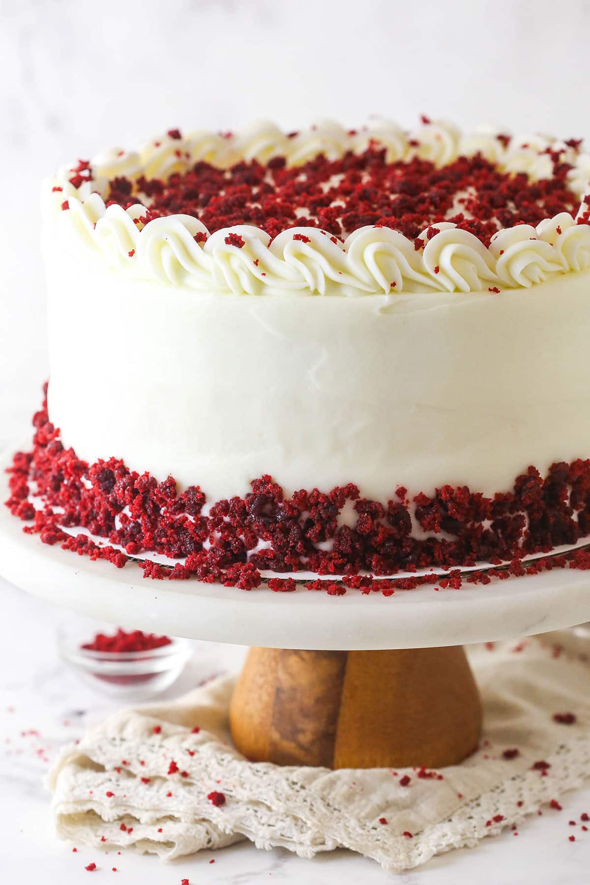 red velvet cheesecake cake on marble and wood cake stand