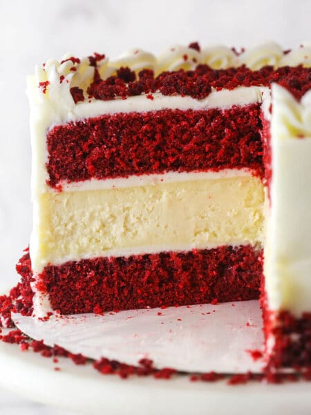 red velvet cheesecake cake on cake stand with piece cut out