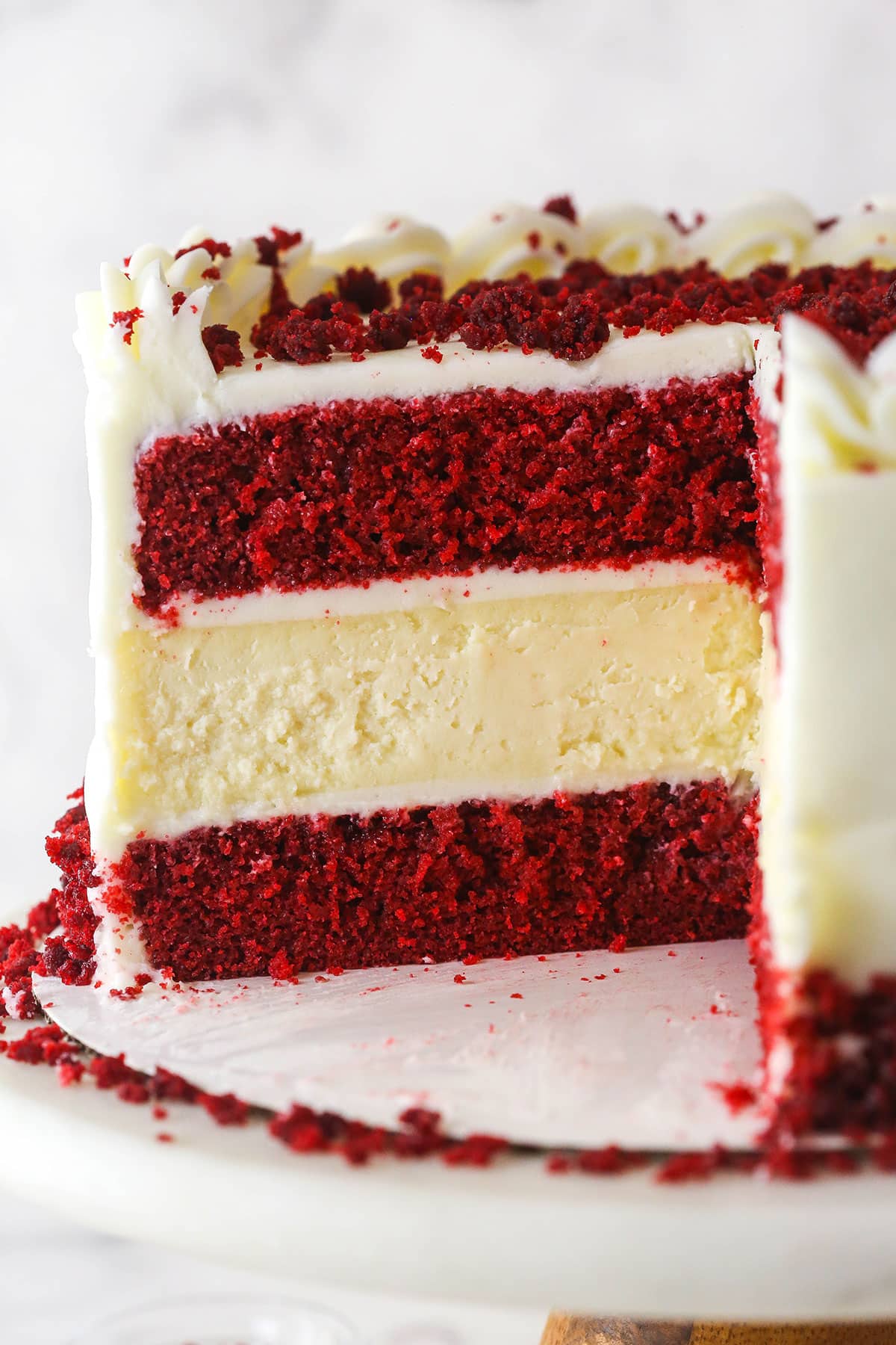red velvet cheesecake cake on cake stand with piece cut out