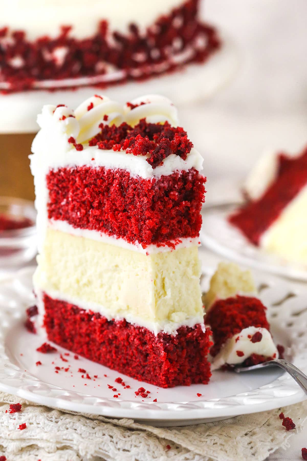 red velvet cheesecake cake slice on white plate with bite taken