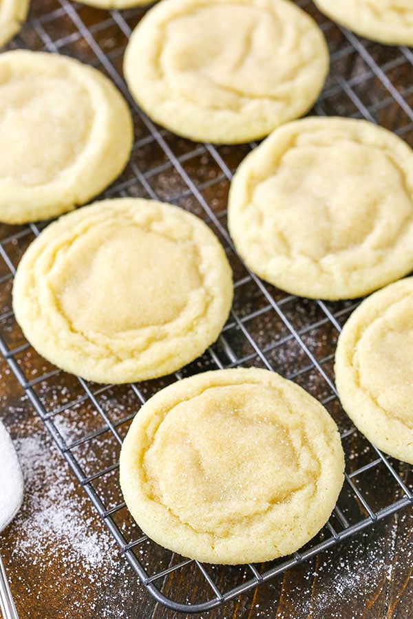Six soft sugar cookies on a cooling rack with sugar sprinkled on the counter