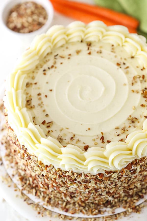 Overhead view of a whole carrot cake covered in cream cheese frosting and pecans 