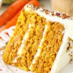 A slice of homemade carrot cake with cream cheese frosting on a white plate
