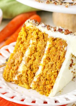 A slice of homemade carrot cake with cream cheese frosting on a white plate