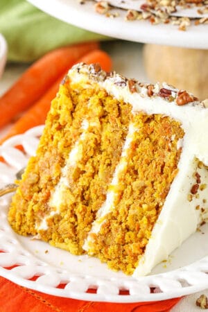 A slice of homemade carrot cake with cream cheese frosting on a white plate