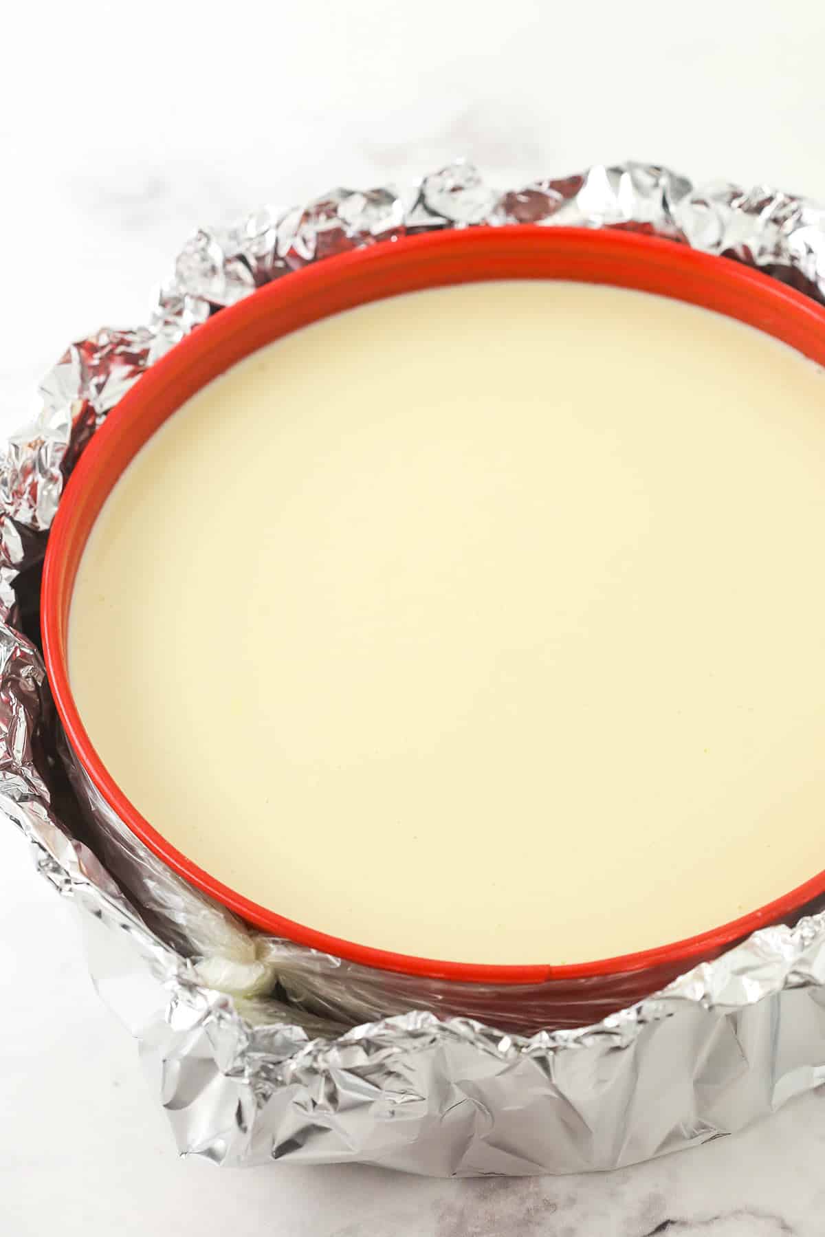 A cheesecake with tin foil around it ready to bake