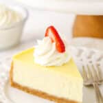 A slice of homemade cheese cake with whipped cream and strawberries