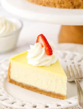 A slice of homemade cheese cake with whipped cream and strawberries