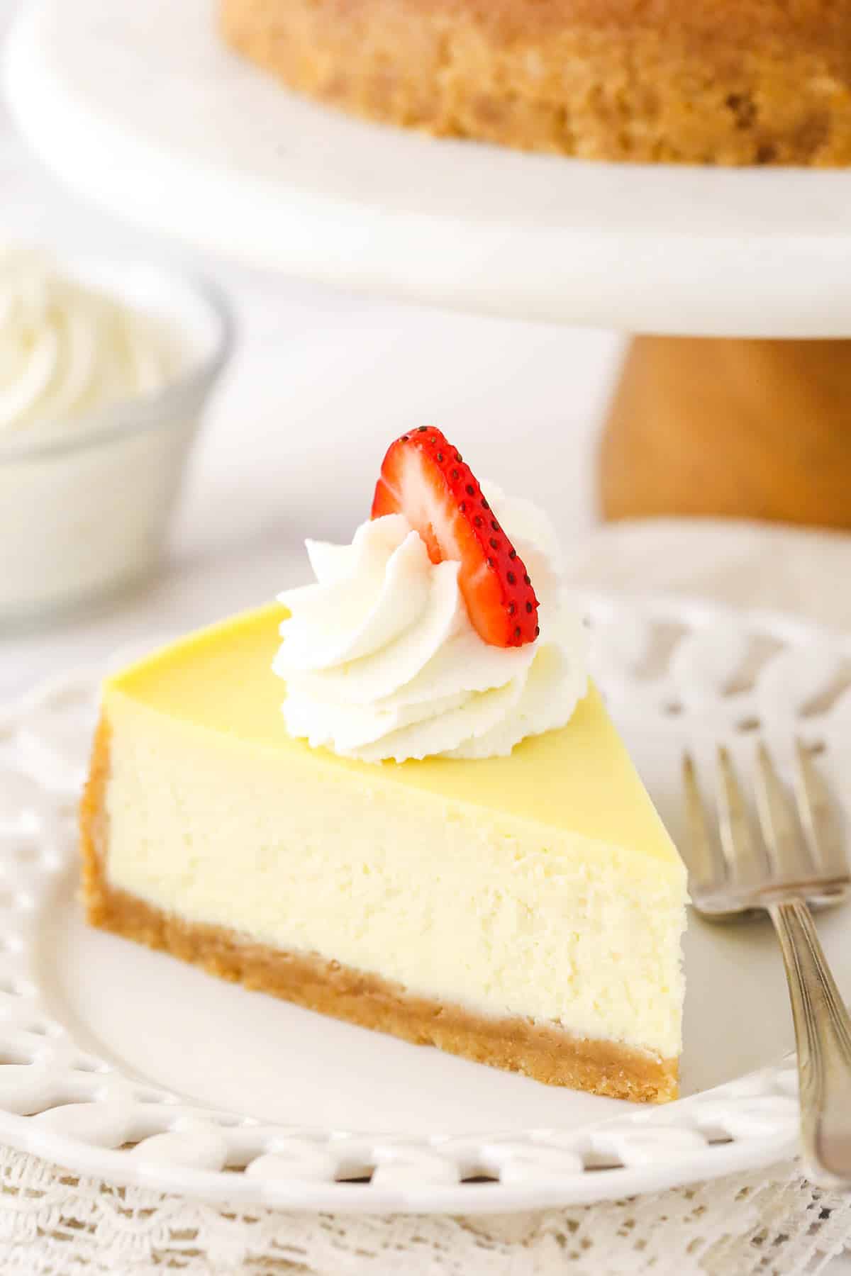 A slice of homemade cheese cake with whipped cream and strawberries