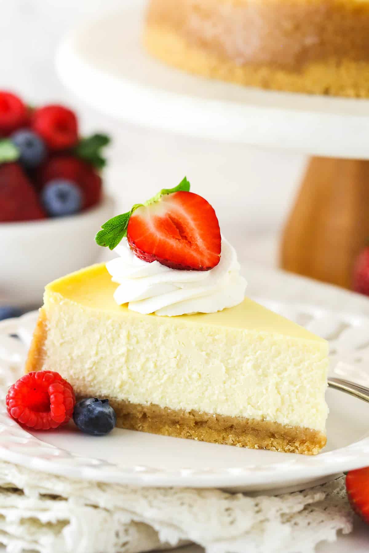 A slice of homemade cheesecake with whipped cream and berries