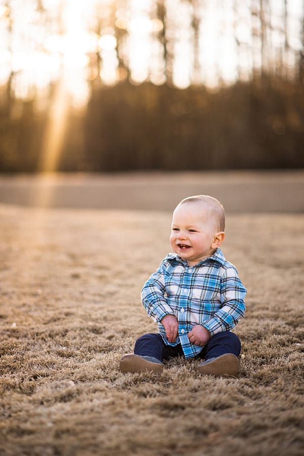 ashton sitting in the grass smiling