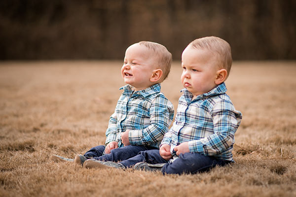 ashton and brooks sitting in grass, ashton smiling and brooks frowning