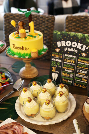 Eight Servings of Banana Pudding on a Serving Platter Next to a Banana Monkey Birthday Cake