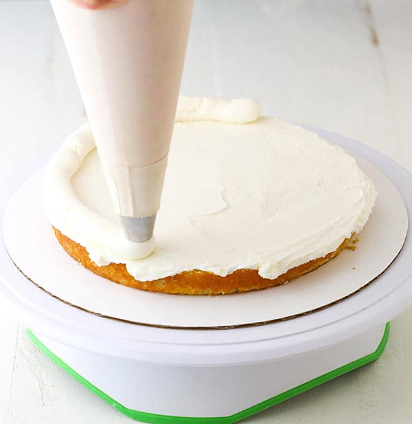 piping a buttercream dam onto cake