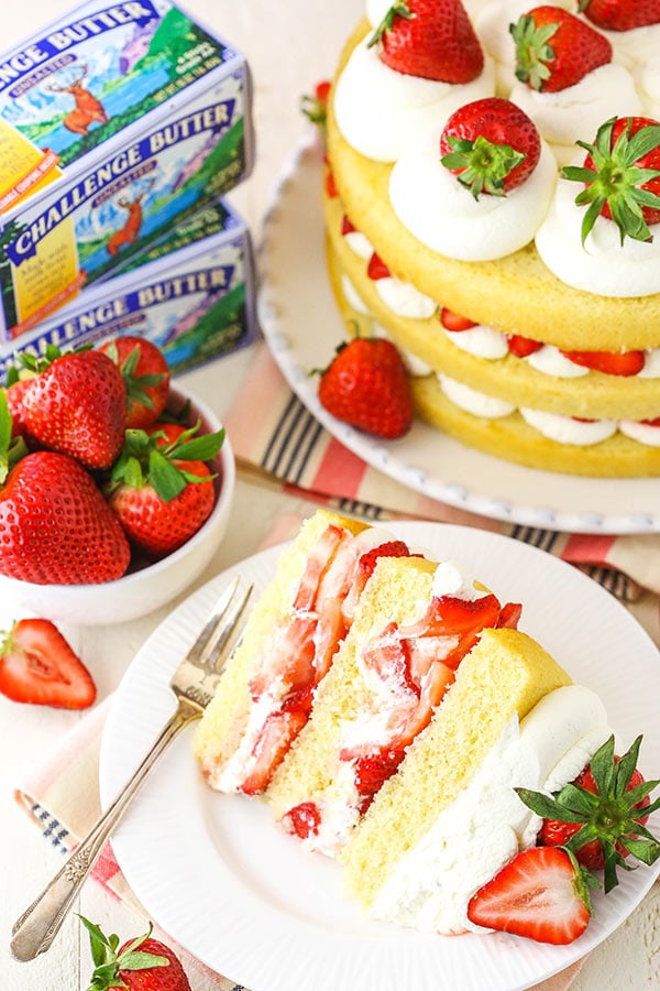 slice of strawberry shortcake cake with full cake in the background
