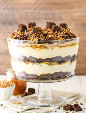 A caramel cheesecake brownie trifle inside of a large glass trifle dish