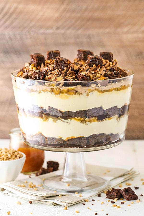 A caramel cheesecake brownie trifle inside of a large glass trifle dish