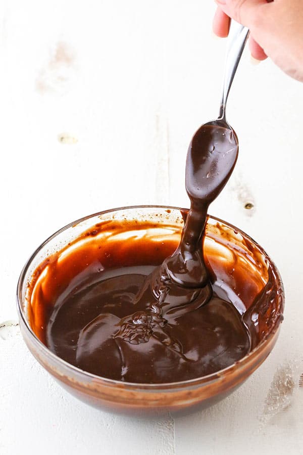 testing chocolate ganache consistency on the side of a bowl