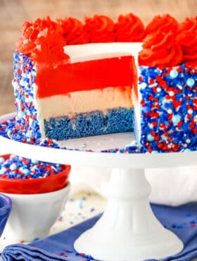 Red white and blue layer cake with sprinkles on the side.
